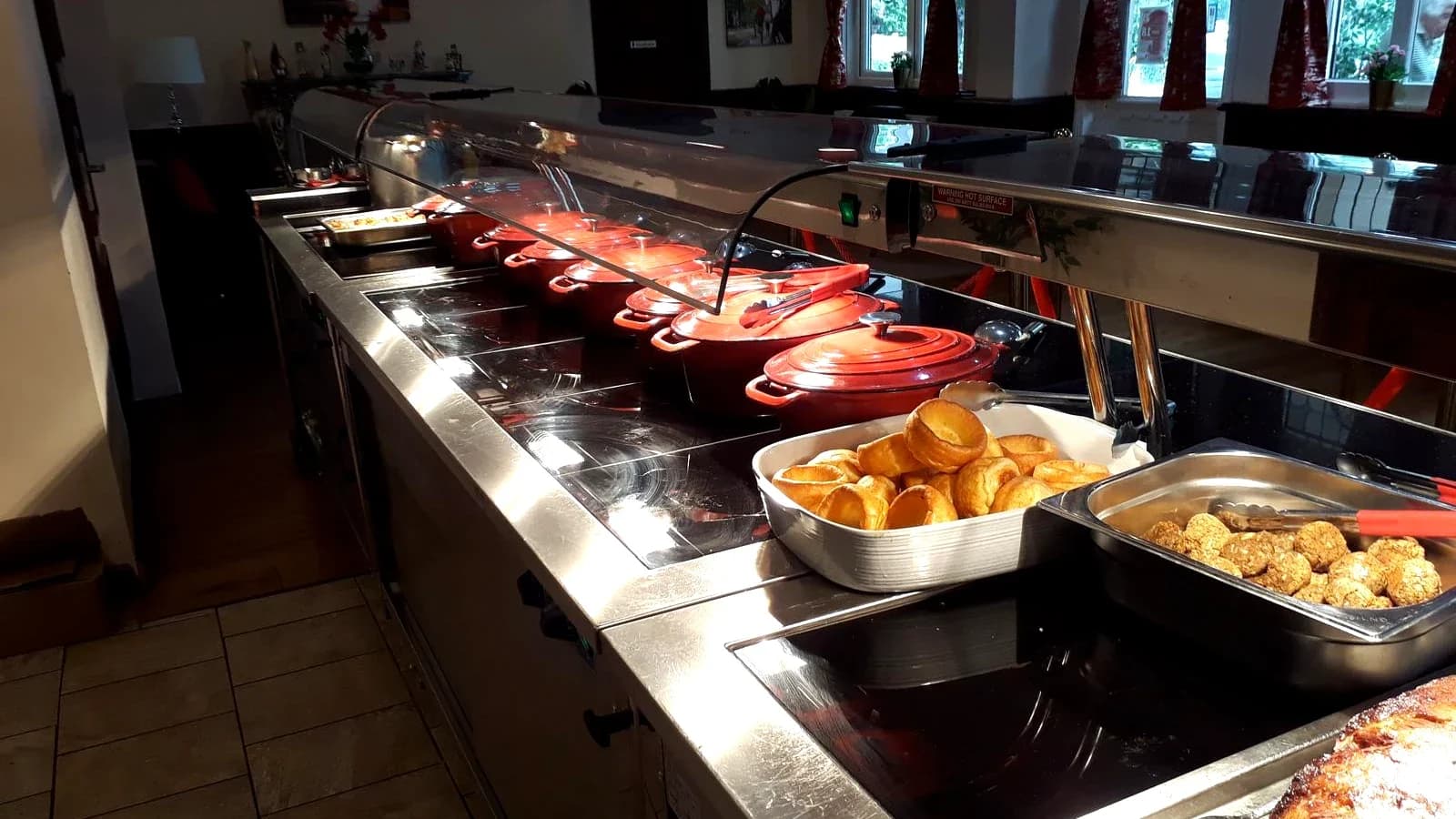 A carvery service counter set up with hot dishes and Yorkshire puddings
